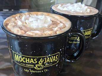 A coffee mug with the label 'Mochas & Javas' belonging to Mocha Jas, filled with steaming mocha coffee.