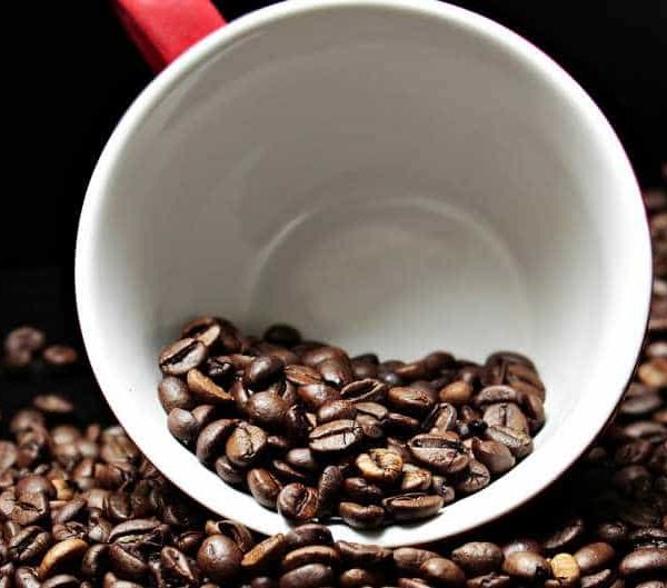 Scattered coffee beans on black background.