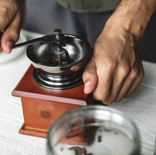 Person grinding coffee beans in small wooden traditional grinder