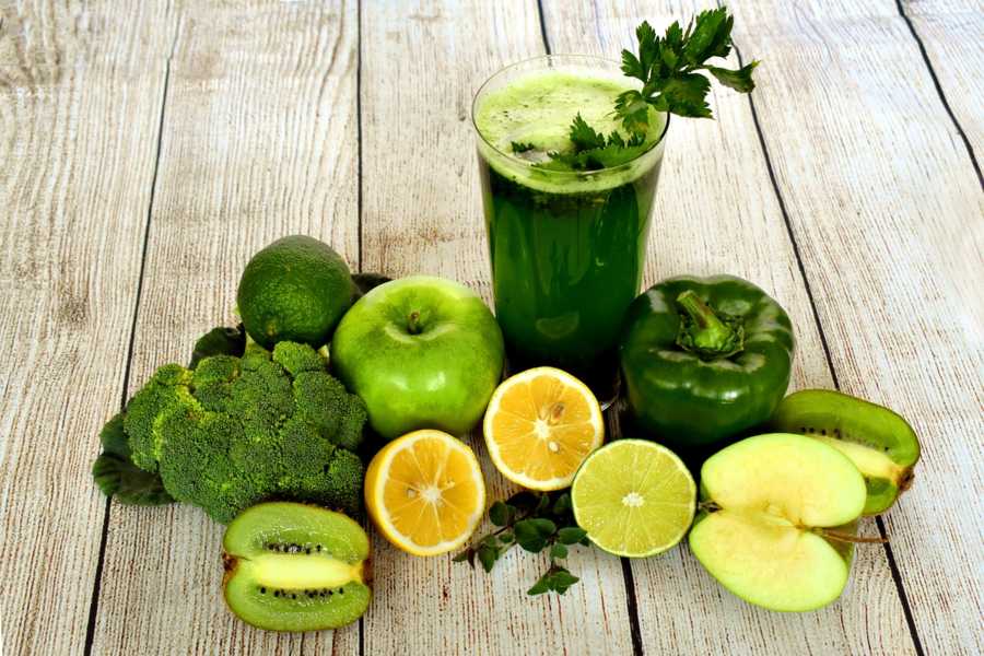 A selection of vegetarian fruits and vegetables around a green smoothie