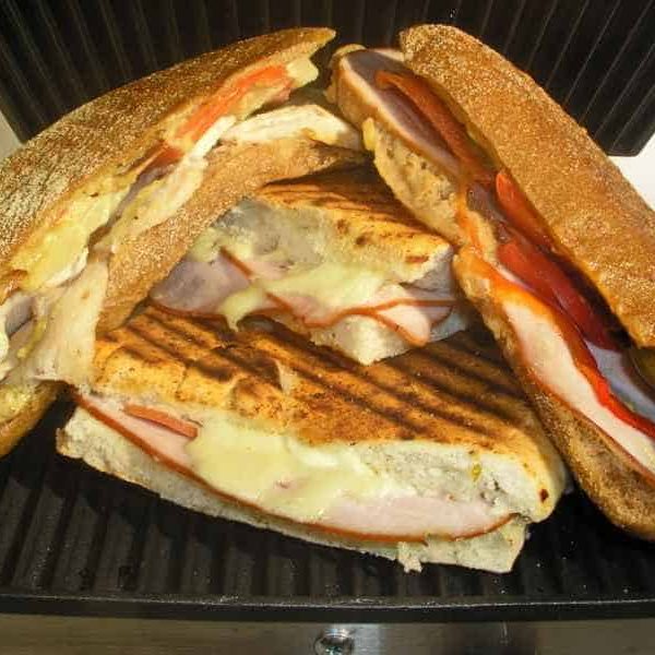 Two panini sandwiches cut in half and stacked on a grill