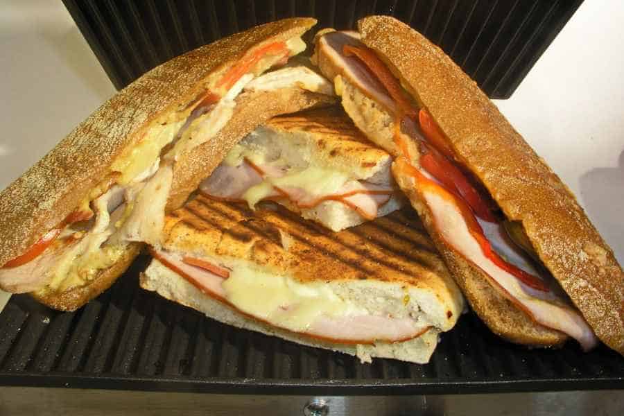 Two panini sandwiches cut in half and stacked on a grill