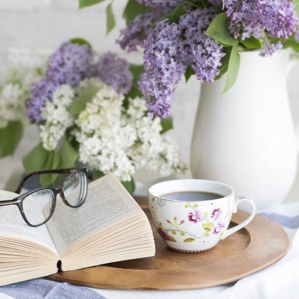 Cup of coffee on table with book and purple flowers