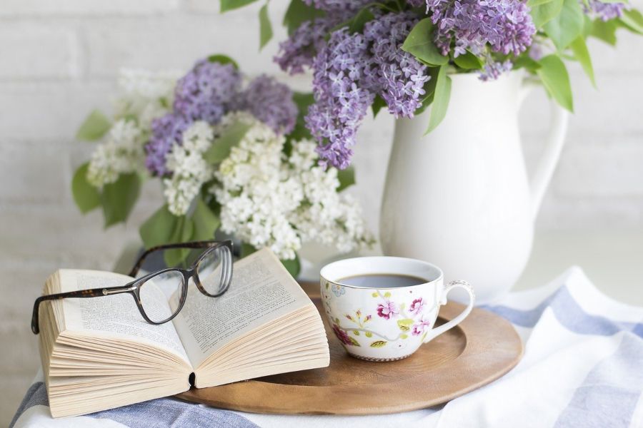 Cup of coffee on table with book and purple flowers