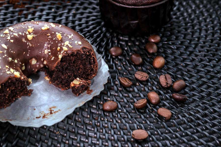 Chocolate doughnut with a coffee glaze next to coffee beans