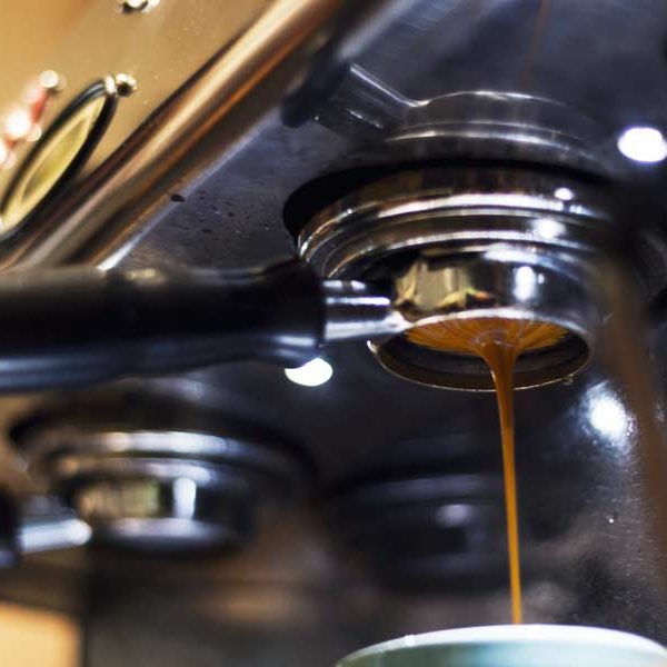 Close-up of a commercial espresso machine pulling a shot