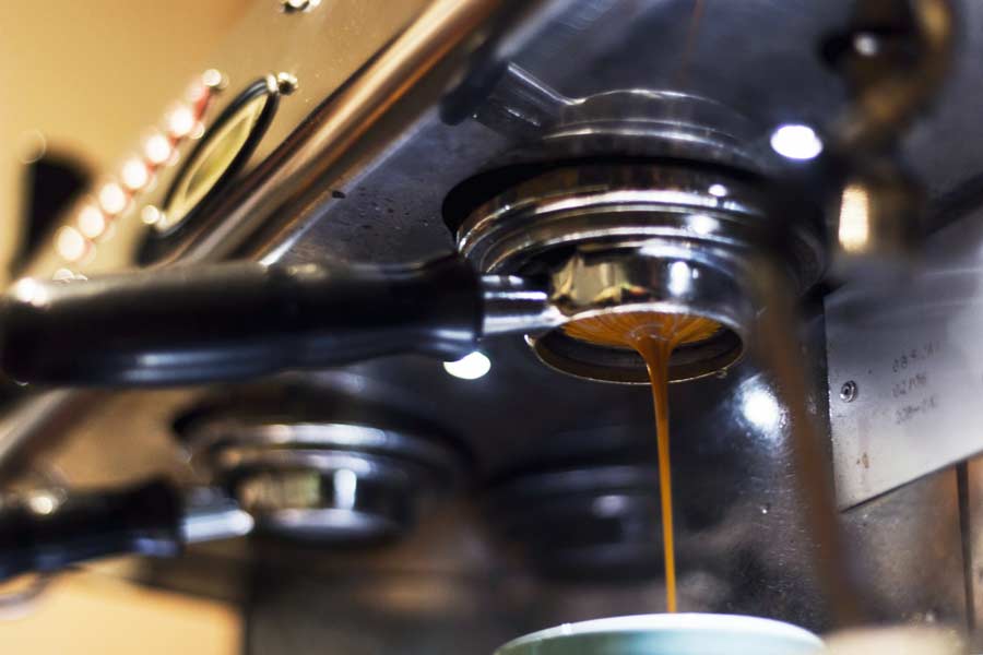 Close-up of a commercial espresso machine pulling a shot