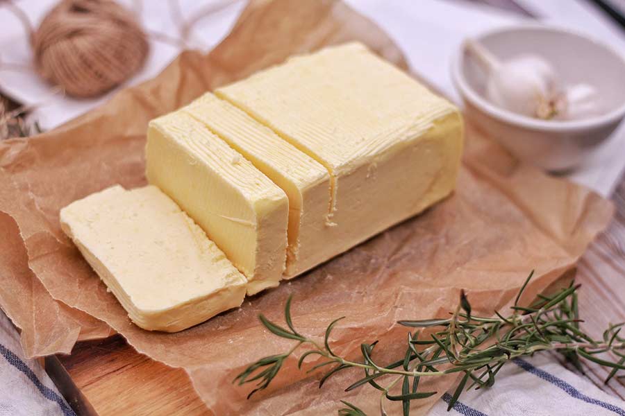 Sliced block of grass-fed butter next to garlic and herbs