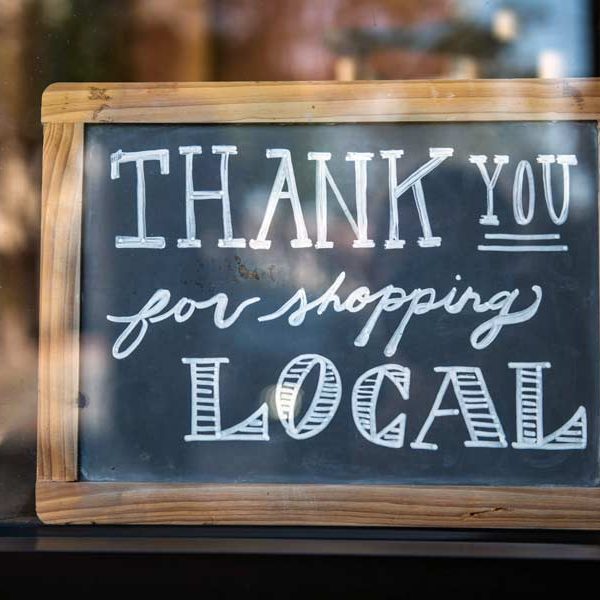 A chalk board in a window in a Frisco Tx Coffee Shop with the words "Thank you for shopping local" on it.