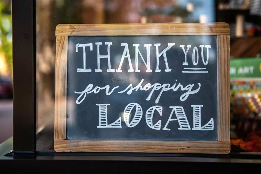 A chalk board in a window in a Frisco Tx Coffee Shop with the words "Thank you for shopping local" on it.