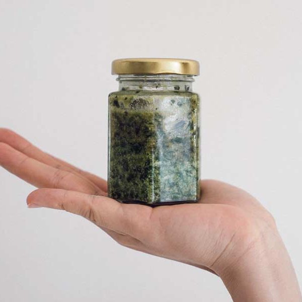 Hand presenting a jar of pesto