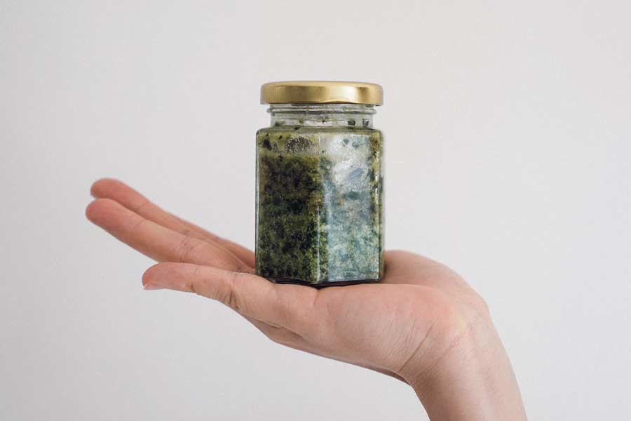 Hand presenting a jar of pesto