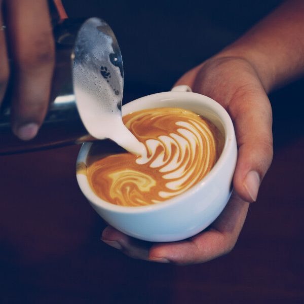 Close up of a barista pouring milk into a latte.