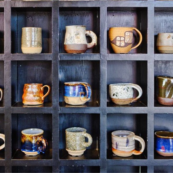 coffee mugs made out of stoneware on a cool black shelf with cubbies