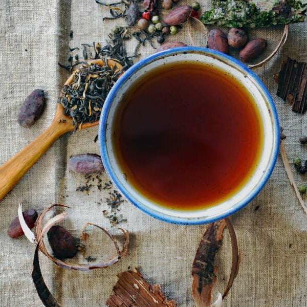 cup of tea surrounded by some tea leaves