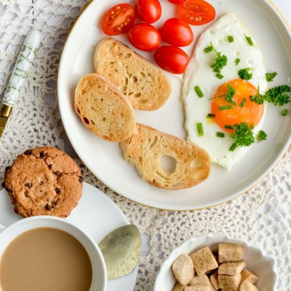 Delicious breakfast plate with a perfectly cooked egg, fresh tomatoes, and toasted bread, served alongside a steaming cup of San Marcos coffee