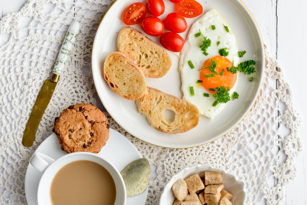 Delicious breakfast plate with a perfectly cooked egg, fresh tomatoes, and toasted bread, served alongside a steaming cup of San Marcos coffee