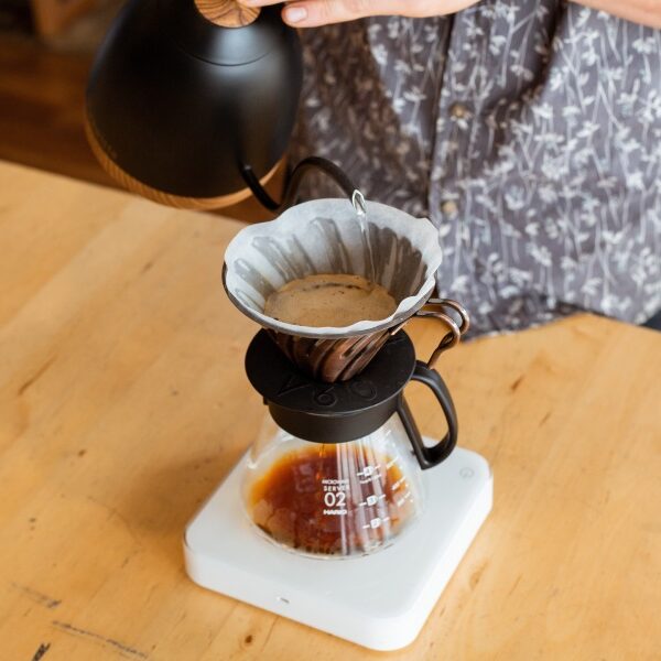 person pouring hot water over a drip coffee maker