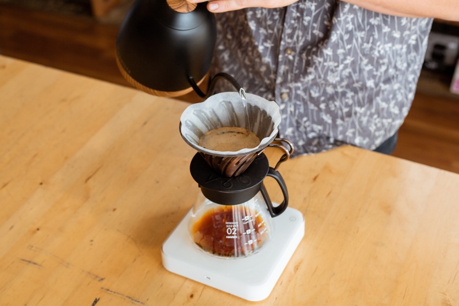 person pouring hot water over a drip coffee maker