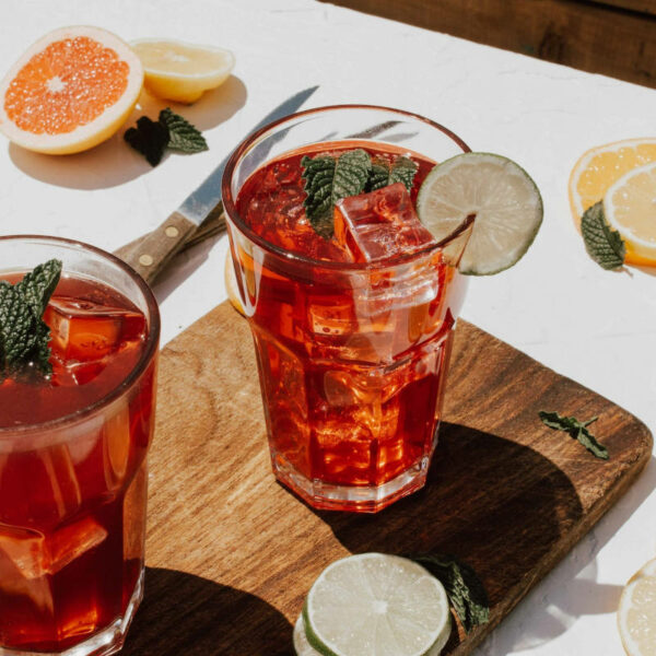 2 refreshing glasses of iced kombucha with fruit slices on a tasting board that you can order from drive thru in Frisco TX