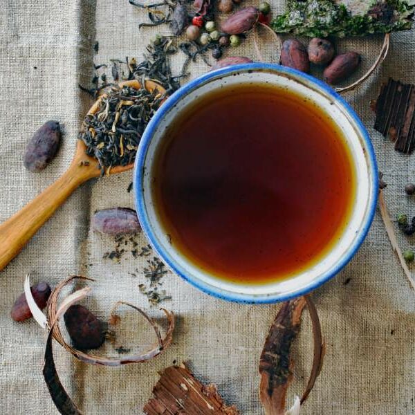 a cup of tea and some tea leaves viewed from above on a linen table cloth