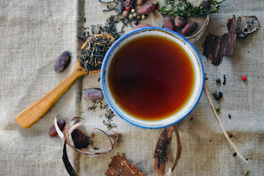 a cup of tea and some tea leaves viewed from above on a linen table cloth