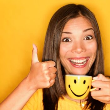 An image showing a woman smiling after having a morning cup coffee