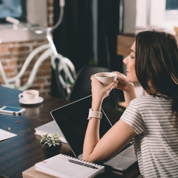 An image of a woman working at a Cafe drinking a cup of coffee during the morning