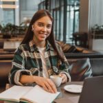 A student smiling while studying at a coffee shop in San Marcos.