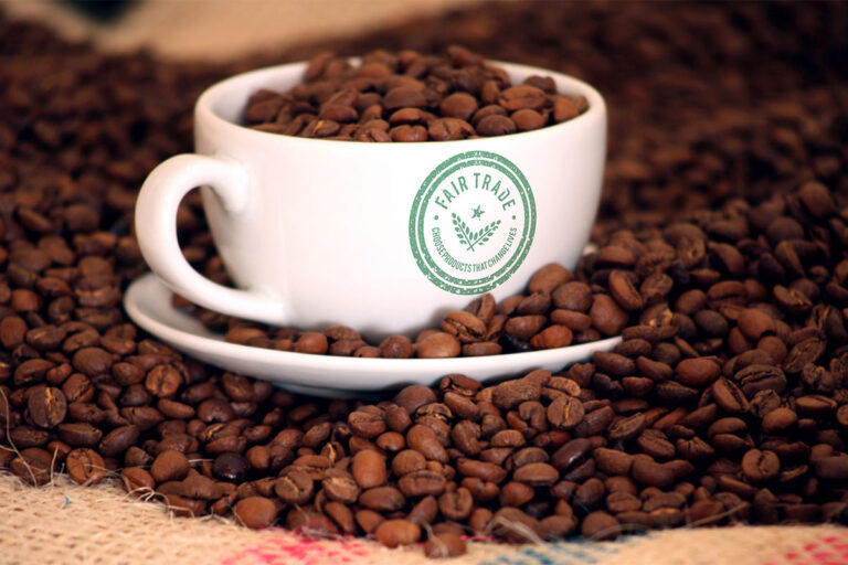 Coffee beans surround a coffee cup with a "Fair Trade" graphic on the cup.